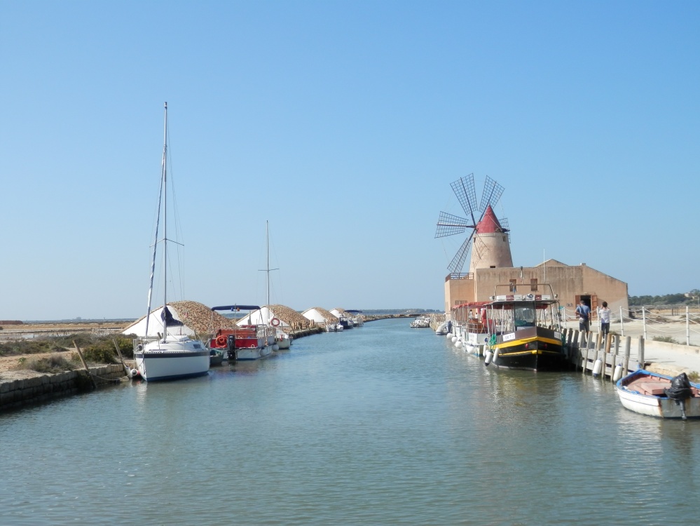 Salt works at Marsala. The windmill you can see is used for milling very large salt rocks into smaller pieces. on the left you can see heaps of salt, protected from the rain by terracotta roof tiles. The salt extracted from the sea is left like this for the 6 winter months to continue drying out. 