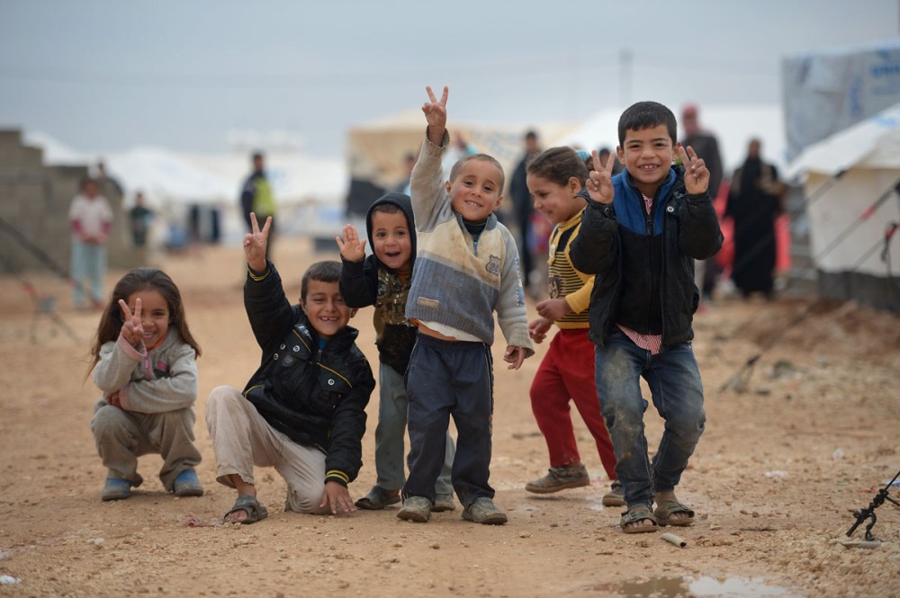 ZA'ATARI, JORDAN - FEBRUARY 01: Children pose for a picture as Syrian refugees go about their daily business in the Za'atari refugee camp on February 1, 2013 in Za'atari, Jordan. Record numbers of refugees are fleeing the violence and bombings in Syria to cross the borders to safety in northern Jordan and overwhelming the Za'atari camp. The Jordanian government are appealing for help with the influx of refugees as they struggle to cope with the sheer numbers arriving in the country. (Photo by Jeff J Mitchell/Getty Images) ORG XMIT: 160600686