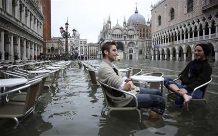 English tourists in St. Mark's Square, Venice; they haven't actually noticed the adverse weather conditions.